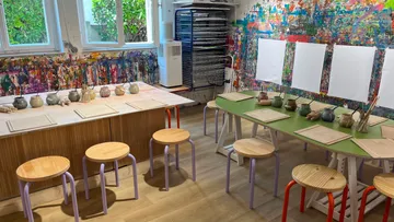 Kunststudio mit Hockern und Tischen.
