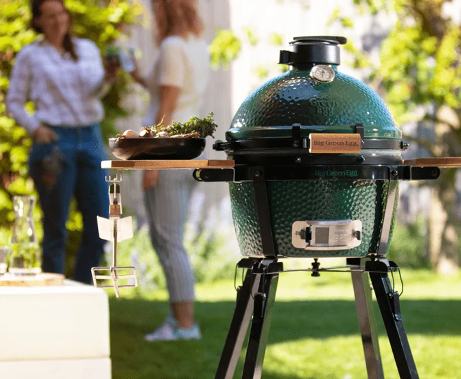 Grill steht in einem Garten, während Menschen entspannen.