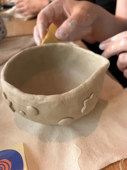 Hände formen Tonschale auf Tisch.