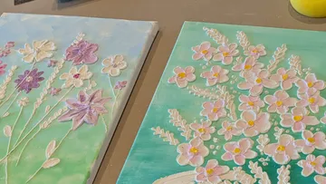 Two floral paintings on a table.