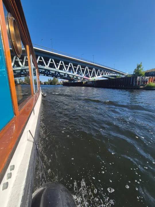 Boot fährt unter Brücke auf Fluss.