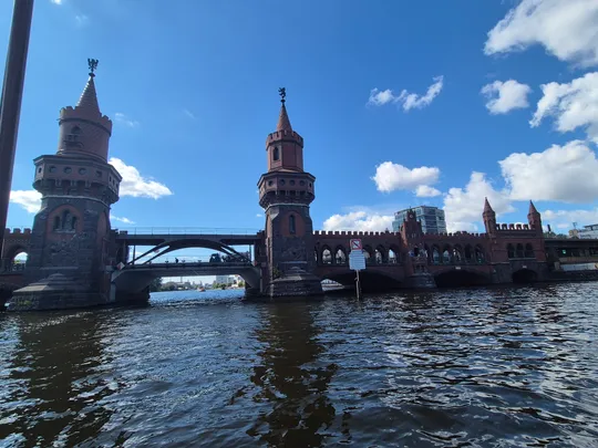 Rote Backsteinbrücke über breiten Fluss unter blauem Himmel.