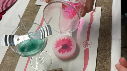 Person pouring pink liquid into flower mold.