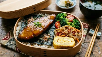 Bento-Box mit Fisch und Gemüse, Holztisch.