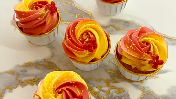 Bunte Cupcakes mit Swirl-Frosting auf Marmor.