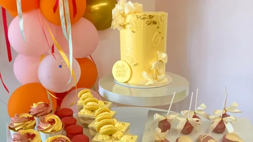 Yellow cake with desserts, balloon backdrop.