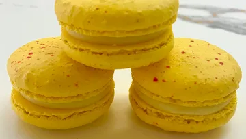 Drei gelbe Macarons auf Tisch gestapelt.