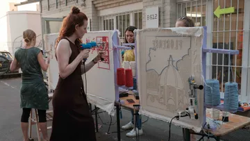 Frauen tufting Stoffleinwand beim Außenworkshop.