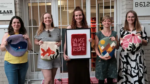 Fünf Frauen halten handgefertigte Textilkunstwerke draußen.