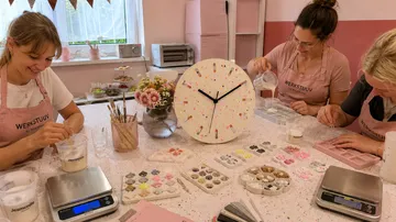 Three women crafting in pastel-themed room.