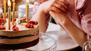 Kuchen mit Kerzen und eine Person daneben.