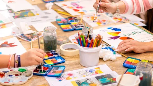 Hands painting at a colorful art table.