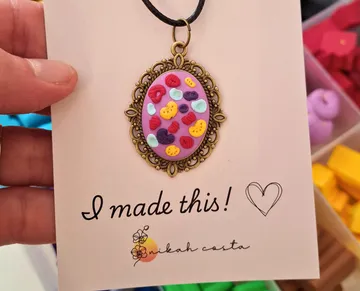 Hand holding crafted pendant in display box.