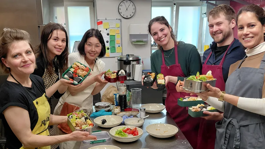 Group preparing and displaying homemade sushi in kitchen.