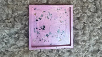 Pink square tray on fluffy gray surface.