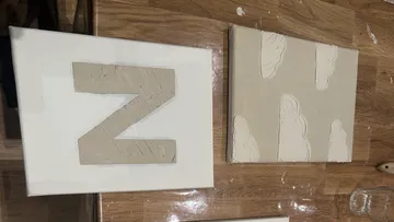 Two textured canvases on wooden surface.