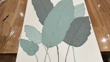 Textured leaf painting on canvas, wooden table.