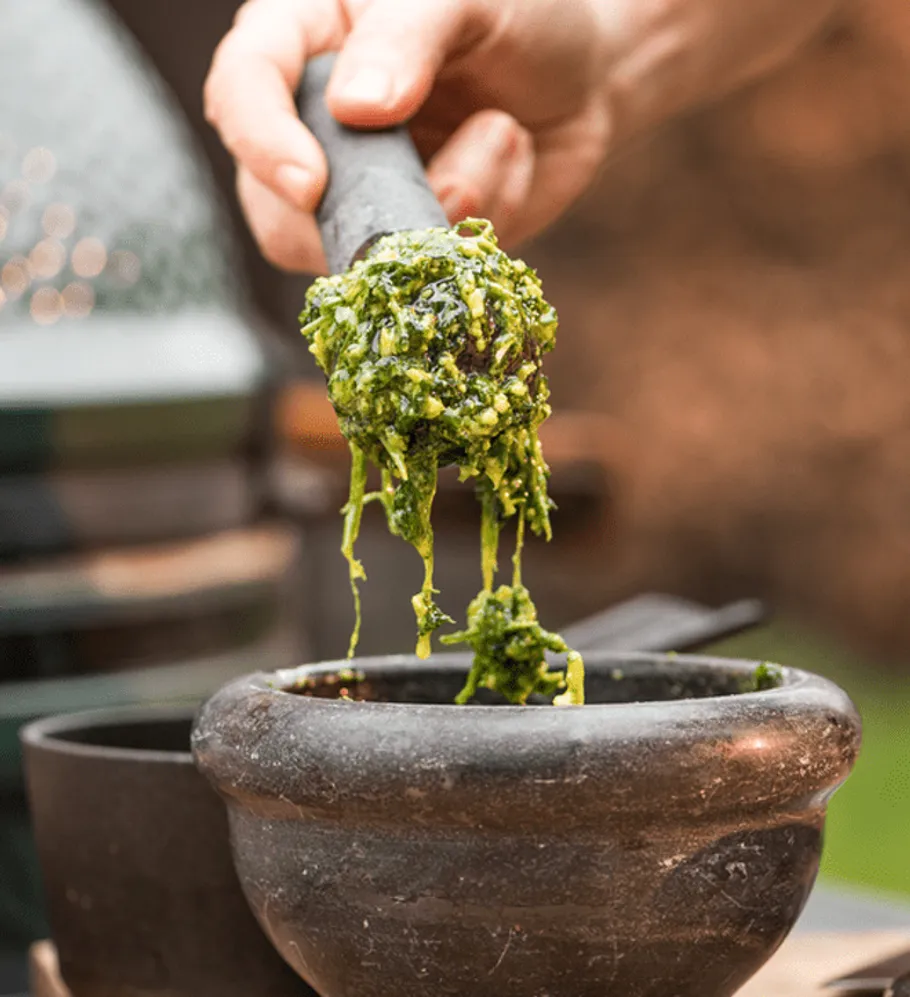 Grünes Pesto wird mit einem Mörser zubereitet.