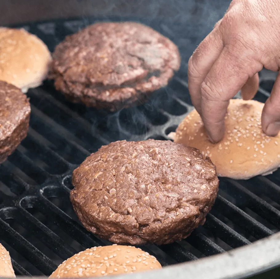 Burger patties are cooked and prepared on a grill.