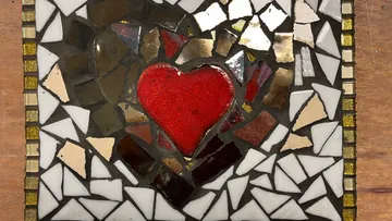 Mosaic heart design on wooden background.