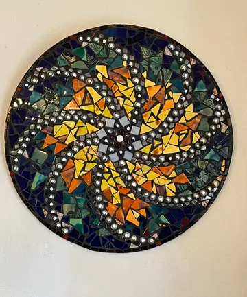 Colorful circular mosaic on beige wall.