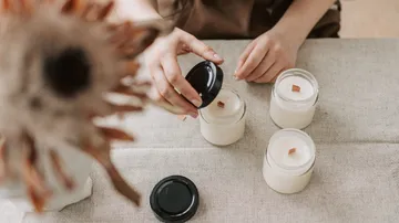 Hands placing lids on candles, table setting.