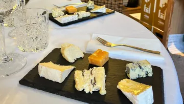 Cheese selection on slate with glassware.