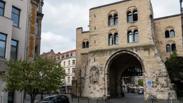 Medieval city gate with bicycles and buildings.