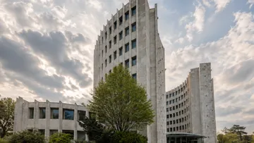 Tall concrete building with cloudy sky.