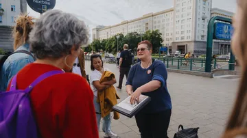 Tour guide speaking to group on city street.