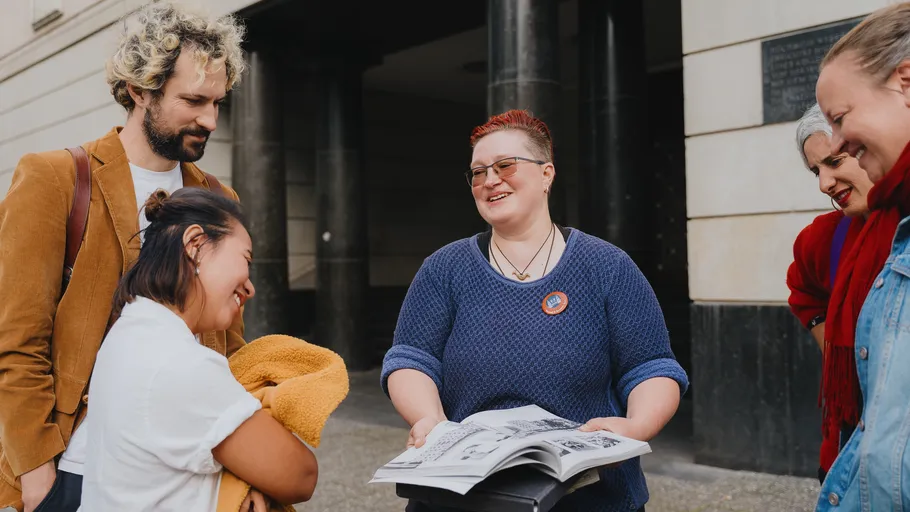 Group of people looking at a photo album outside.