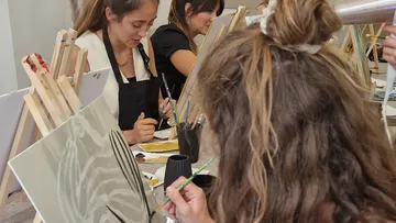People painting on canvases in a studio.