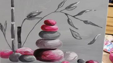 Stacked rocks under bamboo with leaves, gray background.