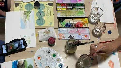 Menschen malen mit Aquarellen am Tisch.