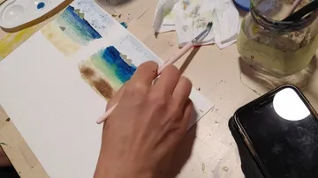 Hand malt auf Papier am Schreibtisch.