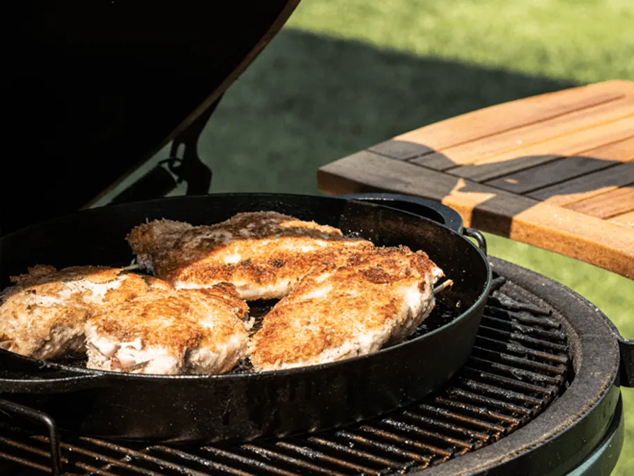 Chicken breasts are fried in a cast iron pan.