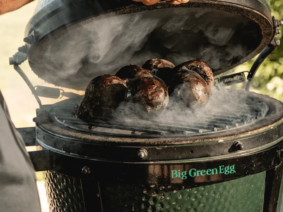 Ein Grill wird geöffnet, während Rauch aufsteigt.