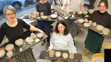 Menschen halten Töpferwaren drinnen.