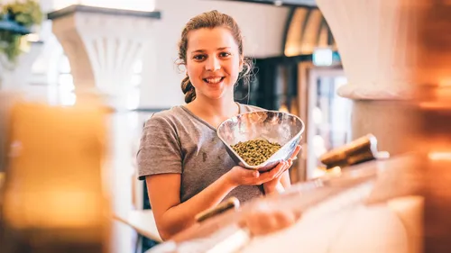 Woman holds bowl in a brewery.