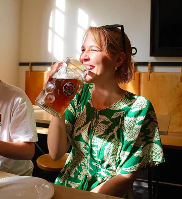Woman drinking beer in sunny room.