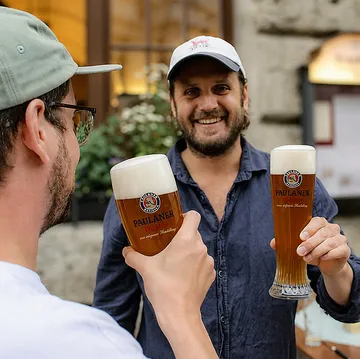 Two men toasting with beer glasses outdoors.
