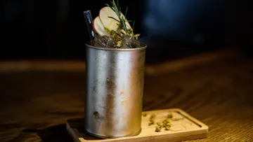 Metallbecher mit Cocktail auf Holztablett.