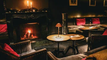 Room with fireplace, chairs, cozy and dimly lit.