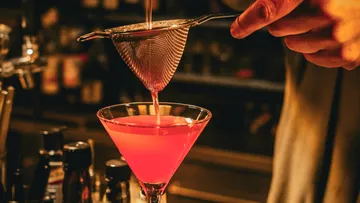 Cocktail strained into glass in bar.
