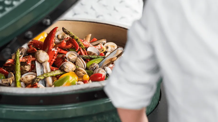 A grill is open, vegetables and seafood are being prepared.