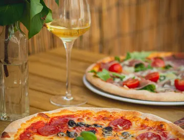 Pizzen und Wein auf Holztisch.