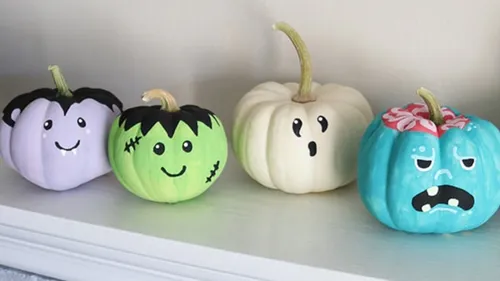 Colorful painted pumpkins on a white shelf.