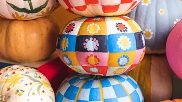Colorful painted pumpkins stacked together.