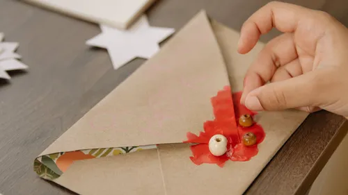 Hand sealing envelope with red wax and beads.