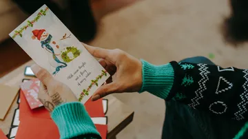 Hands holding festive card with snowman.